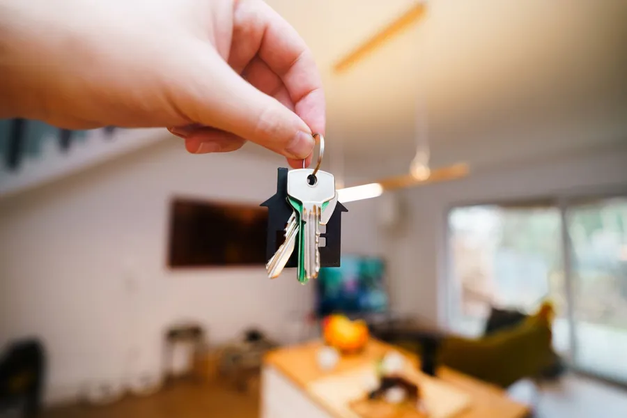 A hand holding a set of house keys inside a bright home